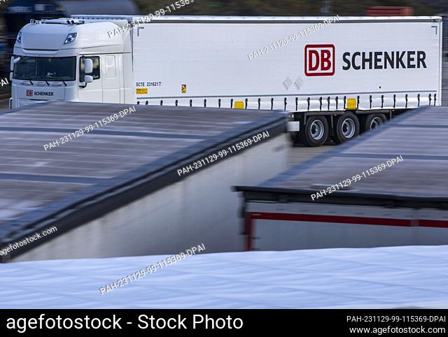 PRODUCTION - 21 November 2023, Mecklenburg-Western Pomerania, Rostock: A truck from the logistics company DB Schenker drives across the site of the logistics...