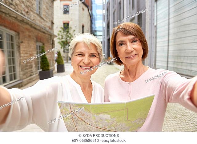 senior women with city map taking selfie outdoors