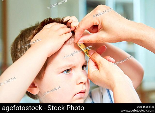 Kind bekommt nach einem Unfall ein Heftpflaster auf die Beule an der Stirn beim Kinderarzt