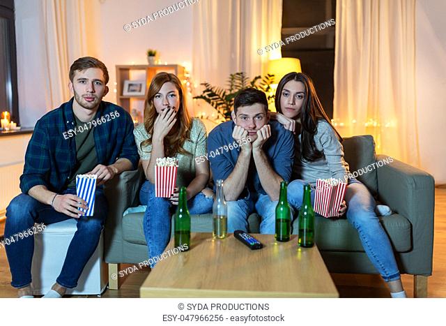 friends with beer and popcorn watching tv at home