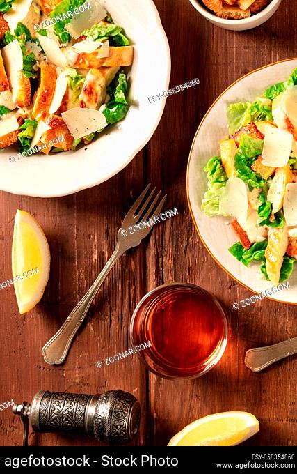 Caesar salad with wine and lemons, top flat lay shot on a dark rustic wooden background