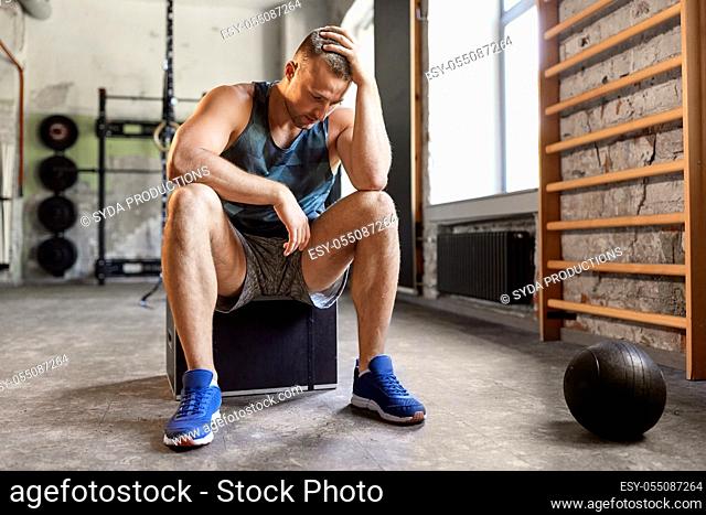 tired young man with medicine ball in gym