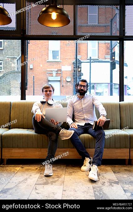 Confident male entreprenuers sitting on sofa in office