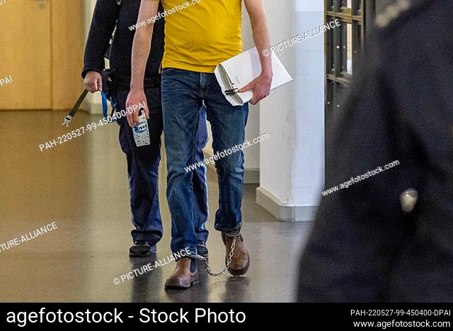 27 May 2022, Bavaria, Regensburg: One of the defendants is led to the courtroom of the Regional Court in shackles. The prosecution accuses two Syrians of...