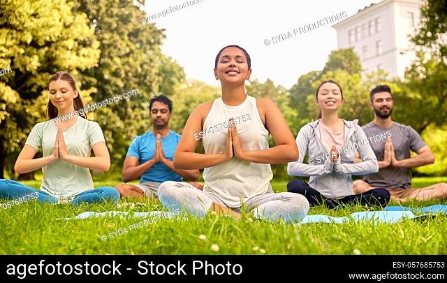 group of people doing yoga at summer park