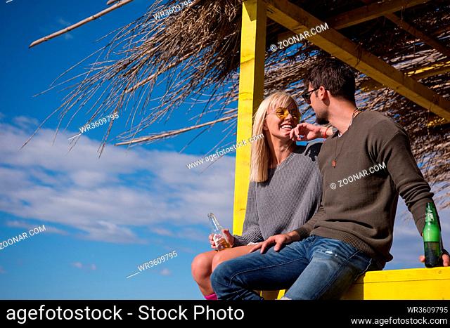Couple Drinking Beer Together in empty beach bar during autumn time