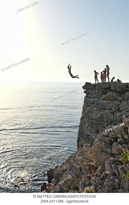 Locals jump from a cliff in Verudela, nearby Pula