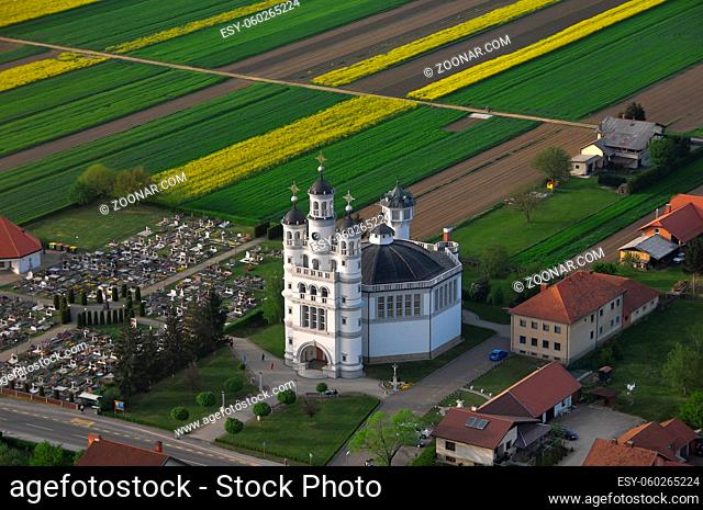 Aerial view of Holy Trinity Church in a small European village in sunset, a cemetery next to the church, unique architecture, Odranci, Slovenia