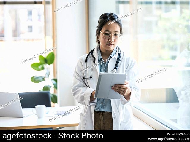 Female doctor using tablet PC by window at hospital