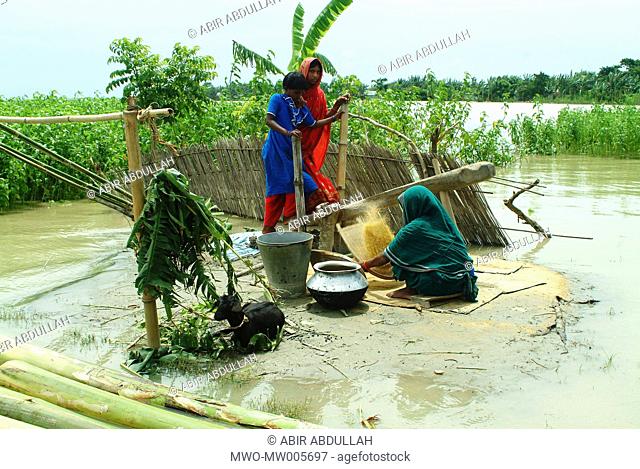 A family members process rice in the only dry place in front of their house Gaibandha, Bangladesh July 21, 2004