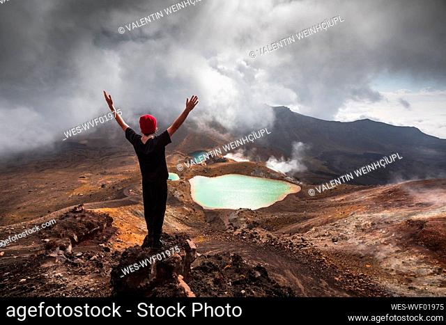 New Zealand, ¶ÿRuapehu¶ÿDistrict, Young man standing with raised arms in front of hot spring in¶ÿTongariro¶ÿNational Park
