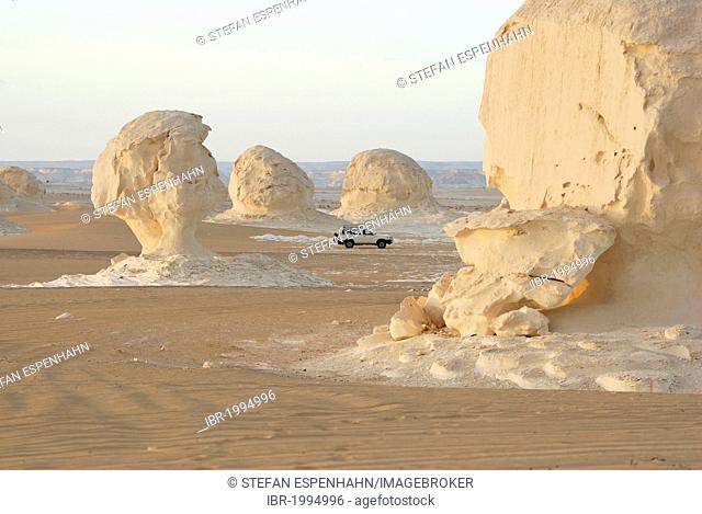 Four wheel drive vehicle among limestone rock formations, White Desert, Farafra Oasis, Western Desert, Egypt, Africa