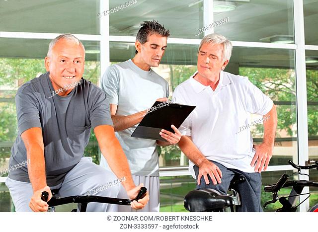 Fitnesstrainer trainiert zufriedene Senioren im Fitnesscenter