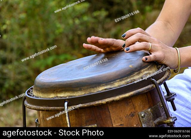 Woman percussionist hands playing a drum called atabaque during brazilian folk music performance