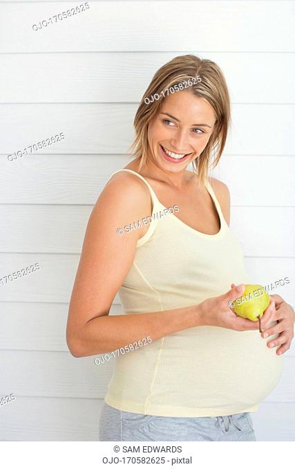 Pregnant woman holding pear