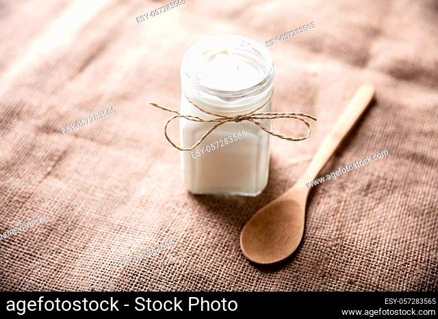An Opened Jar With Yogurt Near Wooden Spoon Over Sack Cloth