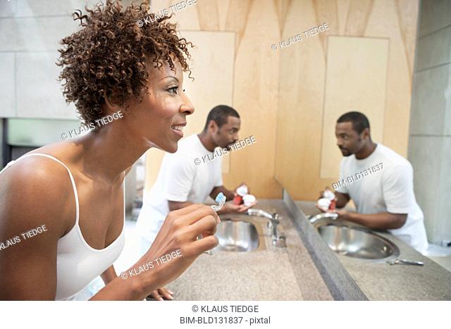 African American couple brushing teeth in bathroom
