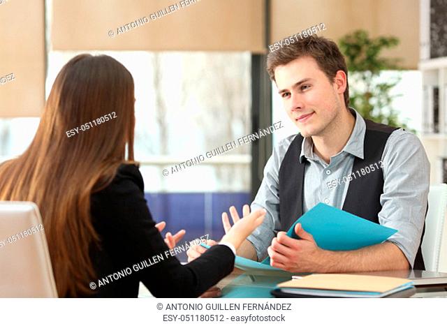Businessman and woman having an interview sitting at office. Woman talks and man listens