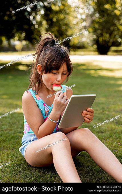 Girl on lawn using digital tablet