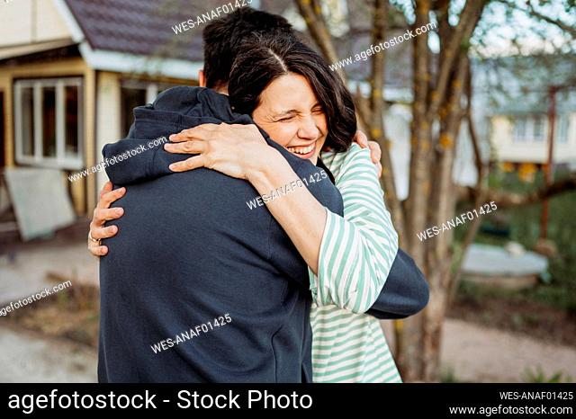 Happy couple embracing in front yard with house in background