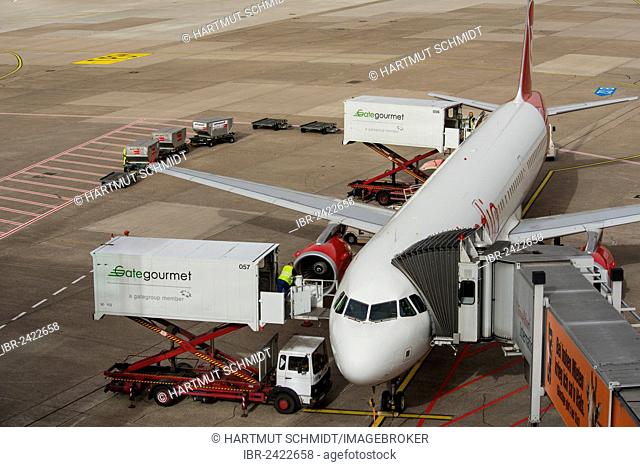 Aircraft is being prepared for the flight, elevating platform truck delivering goods for the galley, baggage car and airplane gangway attached to the aircraft