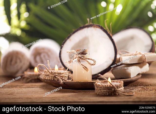 Coconuts and coconut oil on wooden table, on nature background. Health spa background