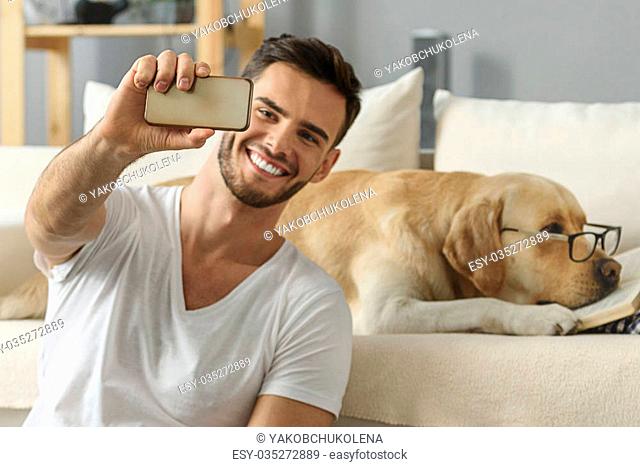 happy man taking a selfie with a bored dog in glasses