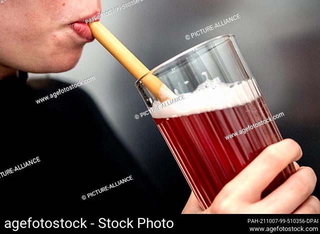 PRODUCTION - 06 October 2021, Lower Saxony, Hanover: A young woman drinks from a glass through a bamboo drinking straw. (to dpa ""Three months of other drinking...
