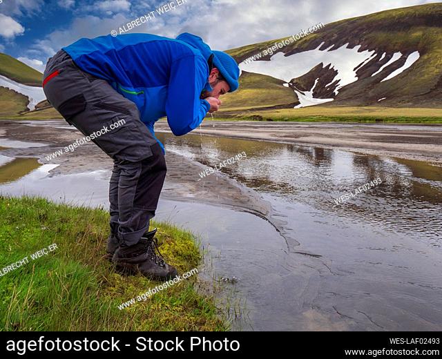 Male tourist drinking water from river