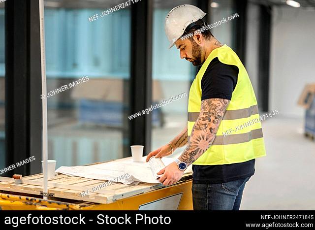 Worker looking at blueprint at construction site