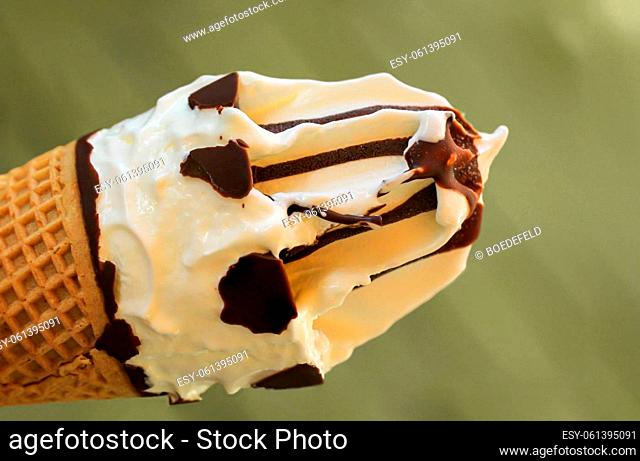 A close-up of a delicious ice cream cone with waffle, vanilla ice cream and chocolate icing