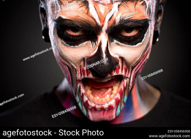 Close view of man with scary skeleton face. Halloween face art, zombie makeup on mans face