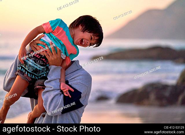 Happy father lifting laughing son on beach