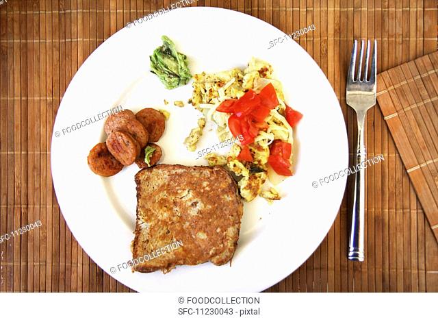 Scrambled egg with tomatoes, sausage and French toast, on a white plate