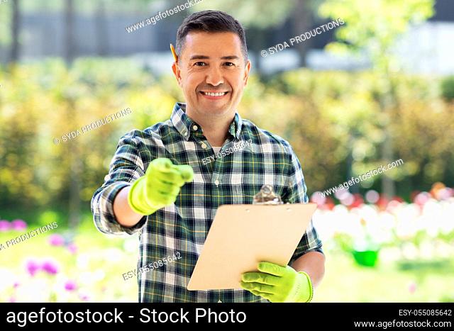 happy smiling man with clipboard at summer garden