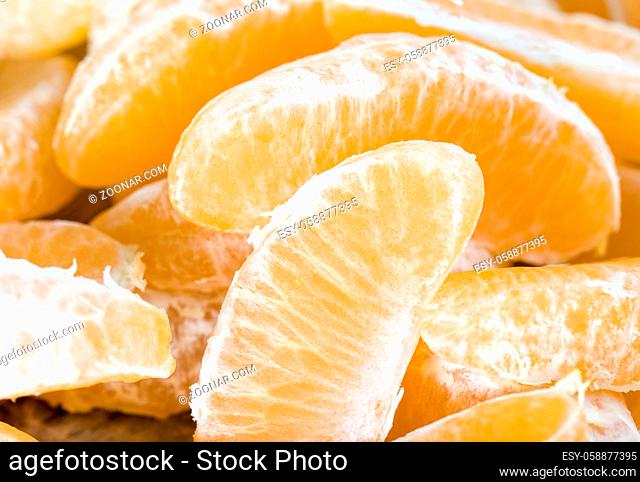 a large number of slices of purified mandarin on a wooden board, close-up of citrus in winter