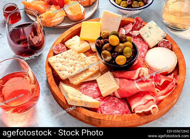 Charcuterie and cheese board with wine and olives. Italian antipasti. Blue cheese, parma ham, salami, salmon sandwiches. Mediterranean delicatessen