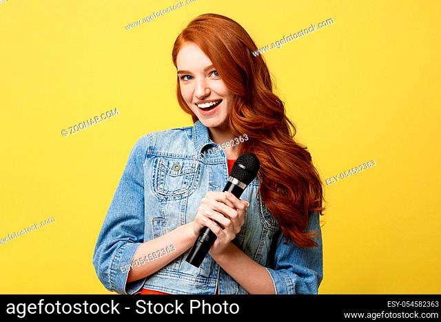 Lifestyle and People Concept: Expressive girl singing with a microphone, isolated bright yellow background