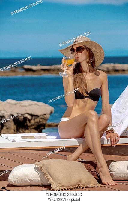 Beautiful woman in bikini drinking juice at the seaside