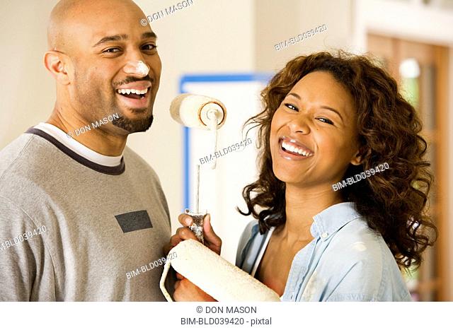 African couple being silly with paint rollers