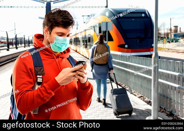man in mask with smartphone traveling by train