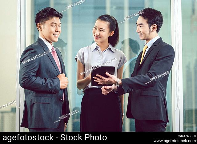 Smiling young businesspeople discussing on digital tablet