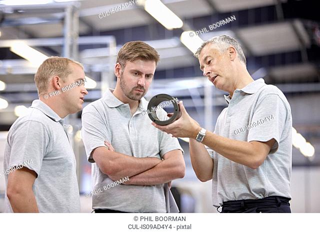 Manager discussing component in engineering factory