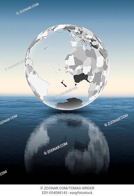 Gambia in red on translucent globe floating above water. 3D illustration