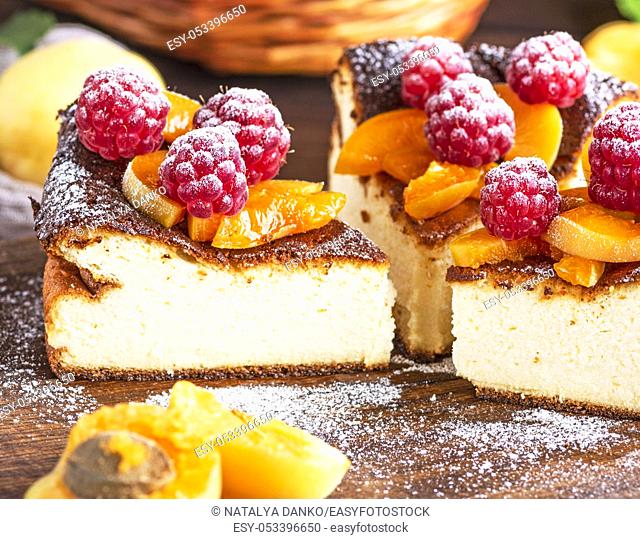 curd pie with raspberries and apricots on a brown wooden board, close up