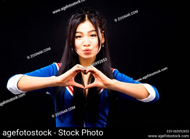 Portrait of beautiful Asian woman showing heart with help of her hands while expressing emotions in studio. Brunette lady with red lips smiling for camera