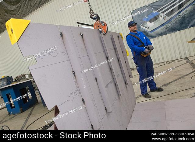 25 September 2020, Mecklenburg-Western Pomerania, Stralsund: A worker is standing at a component of the new electric-solar ferry to lay the keel