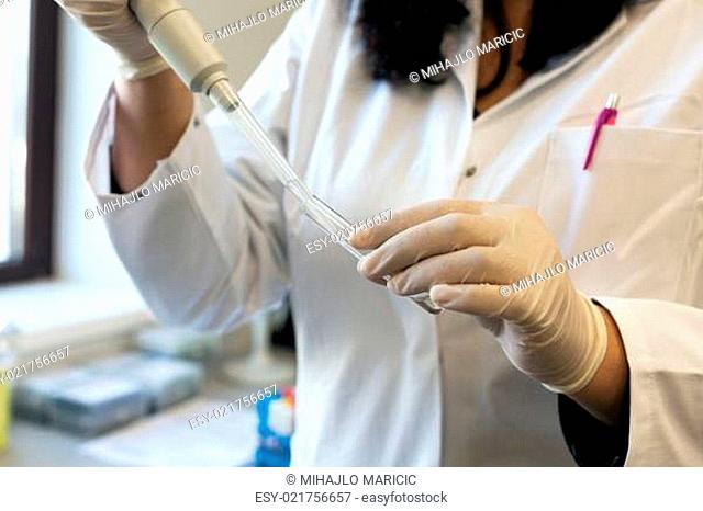 scientist in laboratory filling test tube with pipette