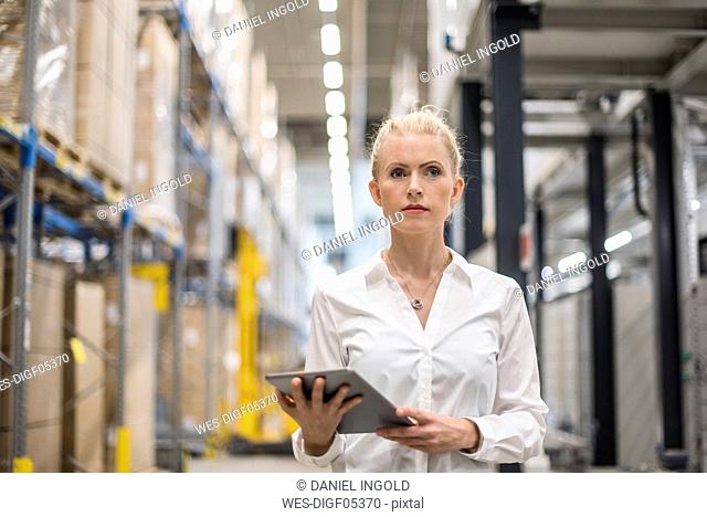 Portrait of woman holding tablet in factory storehouse