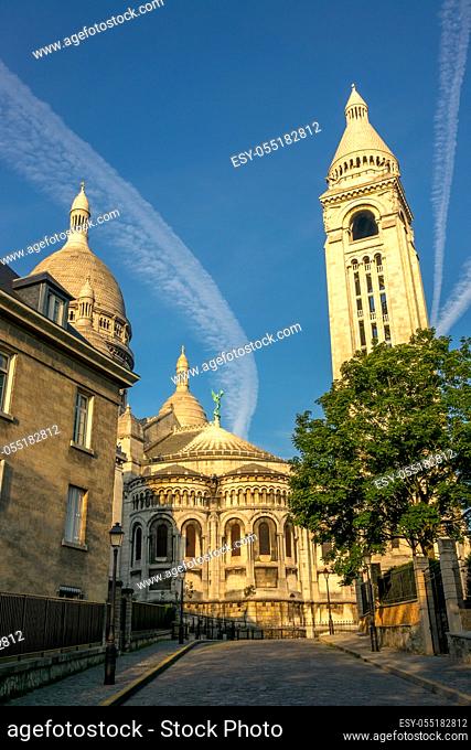 France. Paris. Montmartre. Empty street and bell tower of the Basilica of the Sacred Heart. Summer sunny day and bizarre clouds in the blue sky